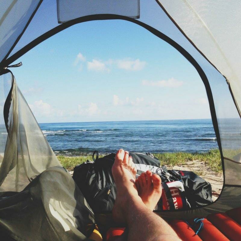 A person lying down within a tent on the beach